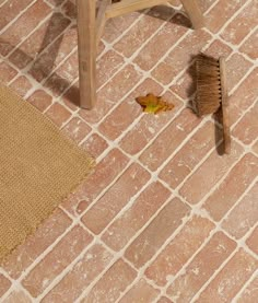 a broom and brush on the ground next to a wooden chair with a brown rug