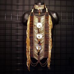 a mannequin is adorned with gold and white beads, chains and fringes