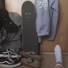 a pair of shoes and a skateboard sitting on the floor next to some clothes