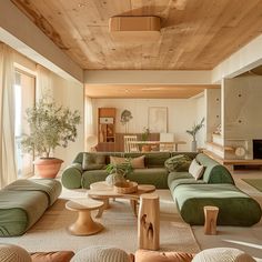 a living room filled with green couches and wooden ceiling beams in an open floor plan