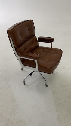 a brown leather office chair sitting on top of a white carpeted floor next to an ottoman