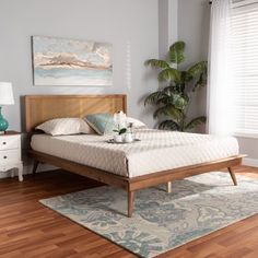 a bed sitting on top of a wooden floor next to a window