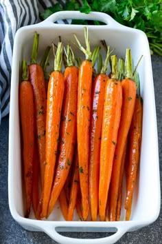 carrots in a white dish with herbs on top