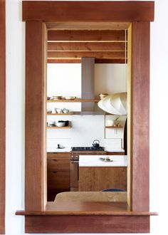 an open doorway shows the kitchen and dining area in this house, with wooden shelves on either side