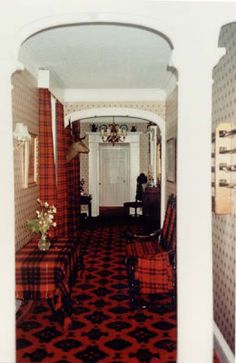 the hallway is decorated with red and black patterned carpet, along with two chairs on either side