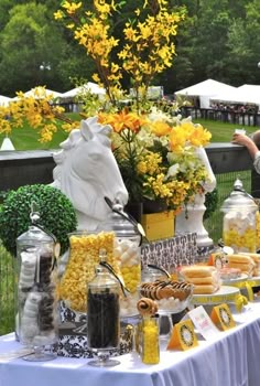 a table topped with lots of food next to a lush green park covered in yellow flowers