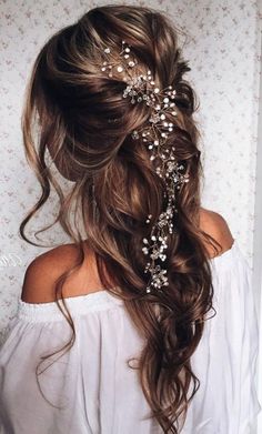 a woman with long hair wearing a flowered headpiece in front of a wall