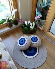 two knitted balls sitting on top of a wooden floor in front of a window