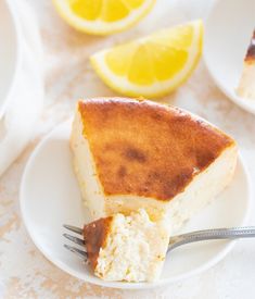 a piece of cake on a white plate with a fork and lemons in the background