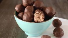 a blue bowl filled with chocolate covered candies on top of a white napkin and wooden table