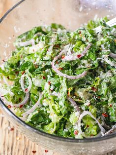 a glass bowl filled with lettuce, onions and red onion sprinkles