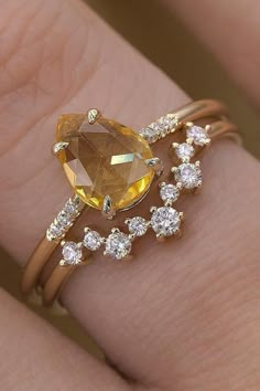 a woman's hand with a yellow and white diamond ring on top of it