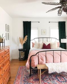 a bed room with a neatly made bed next to a dresser and a ceiling fan