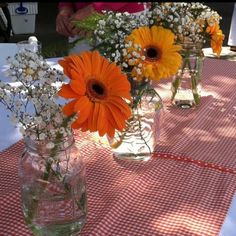 three mason jars filled with flowers sitting on top of a checkered tablecloth covered table