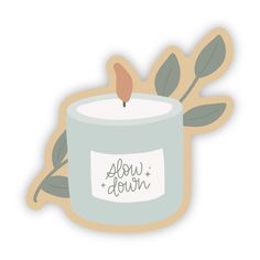 a candle with the words slow down on it and some leaves in front of it