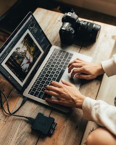 a person sitting at a table with a laptop and camera on the table next to them