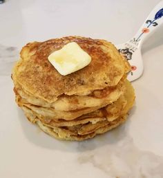 a stack of pancakes with butter on top and a toothbrush next to the stack