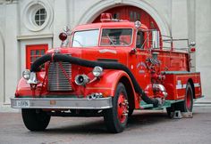 an old red fire truck parked in front of a building