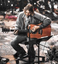 a man sitting in front of a microphone playing a guitar