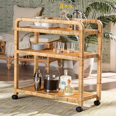 a bamboo bar cart with drinks and glasses on it in front of a living room couch