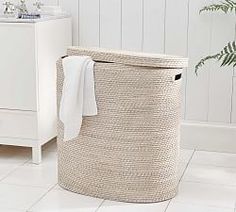 a white bathroom with a large laundry basket