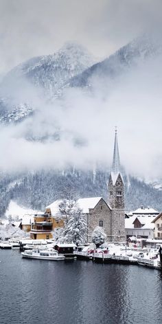 a lake with snow covered buildings and mountains in the background