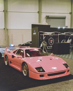 a pink sports car parked in front of a display case