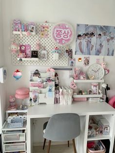 a white desk topped with lots of clutter next to a wall covered in pictures