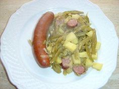 a hot dog and some vegetables on a white plate