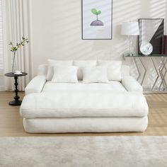 a large white couch sitting on top of a wooden floor next to a table with flowers