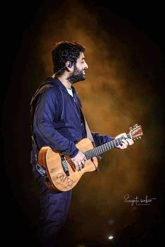 a man playing an acoustic guitar on stage