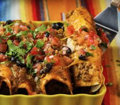 a yellow dish filled with mexican food on top of a table