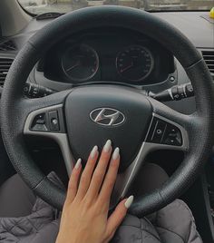 a woman driving a car with her hands on the steering wheel