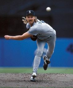 a baseball player pitching a ball on top of a field in the middle of a game