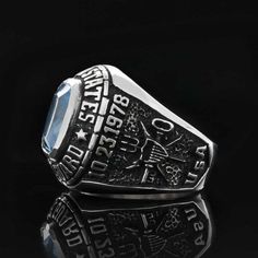 a silver ring with an oval blue stone in the center on a black background,