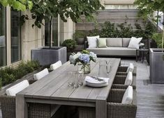 an outdoor dining area with couches, tables and plants on the side of it