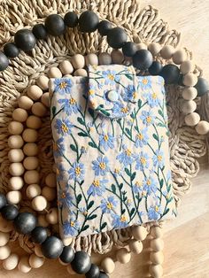 a wooden beaded necklace with a blue and white flowered shirt on it, surrounded by other beads