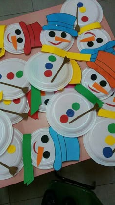 paper plates with snowmen and carrots on them sitting on top of a table