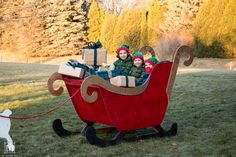 two children are riding in a sleigh with presents