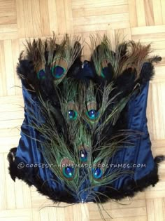 peacock feathers are arranged on a blue piece of cloth with black fur trimmings