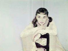 an old photo of a woman sitting in a chair with her hand on the seat