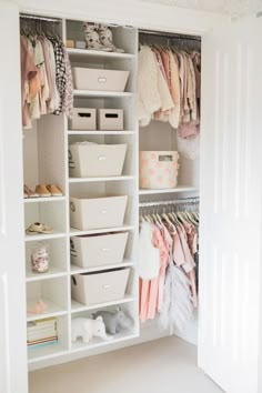 an open closet with clothes and baskets on the bottom shelf, next to a phone