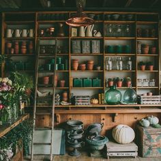 a room filled with lots of pots and vases on shelves next to each other