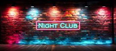 a neon sign that reads night club in front of a brick wall with colorful lights