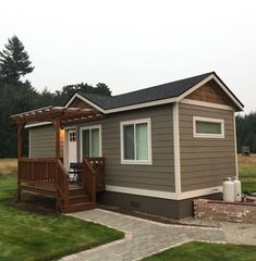 a small house with a porch and covered patio in the front yard on a cloudy day