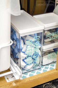 two clear containers filled with blue and white items sitting on top of a wooden shelf