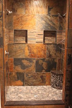 a walk in shower sitting next to a tiled wall and floor covered in brown tile