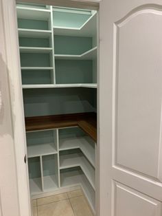 an empty walk in closet with white shelves