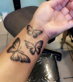 a woman's arm with three butterflies tattooed on the side of her left arm