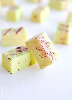 several pieces of cake sitting next to each other on a white counter top with pink and green sprinkles